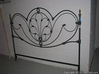 Front view of the king size metal headboard showing decorative curved design and brush gold finials.