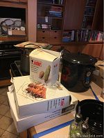 Overview photo showing two roasting pans stacked with Weber cooking accessories on top and the crab pot to the side.