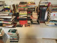 Wide view of multiple book stacks on low shelf against wall