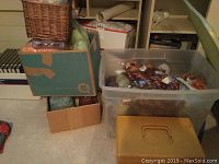 Photo showing stacked cardboard and plastic boxes filled with yarn and craft supplies, a wicker basket on top