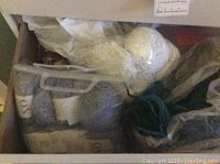 Drawer showing assorted skeins of yarn including white bulky yarn, gray skeins and teal cord
