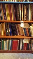 Photo of tall bookshelf filled with numerous coin books and numismatic literature of various sizes and colors.