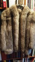 Front view of the gray and light brown women's fur coat on a hanger.