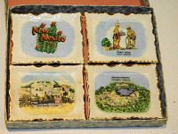 Four porcelain souvenir trays from New Mexico inside an open grey textured box with red interior fabric lining, showing four different printed scenes.