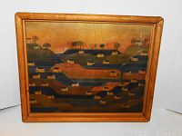 Front view of the signed and dated wood panel art in a wooden frame showing the full painting of houses and hills under an orange sky.