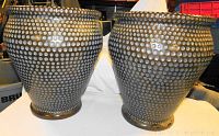 Pair of large matching decorative metal pots with a dotted texture on a white cloth background.