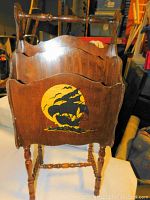 Front view of wooden stand up magazine rack showing dragon design on front panel and turned legs.