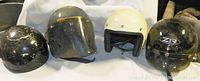 Four helmets arranged side by side showing front and profile views with background sheet.