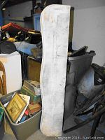 Vertical photo showing marble mantle piece standing upright with visible wear marks and curved top end.