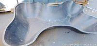 Top view of the large black plastic pond form showing its curved shape and surface texture.