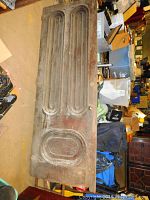 Full view of one wooden antique door with recessed panels, showing finish wear and patina.