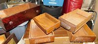 Five different wooden drawers stacked together showing variety in sizes, knobs, and wood finishes.
