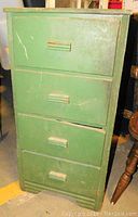 Front view of the green tall chest showing four drawers and visible scratches.