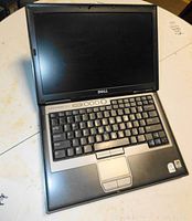 Photo of first Dell laptop opened showing keyboard, screen, and touchpad in used condition