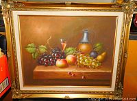 Front view of fruit still life painting including grapes, peaches, cherries, pear, plum, glass and jug in detailed gold ornate frame.