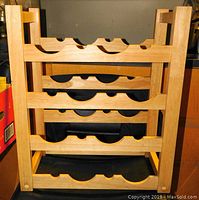 Front view of the wooden wine rack showing four horizontal slatted shelves with bottle cutouts.