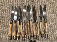 Full set of 11 bone handle knives with detailed metal collars and stainless steel blades arranged on carpeted surface.