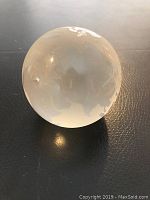 Front view of glass Earth globe paperweight showing etched continents in frosted glass finish.