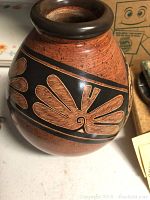 Photo showing the full oval-shaped vase with carved natural leaf motifs on black band, signed by Willy Villafuerte, in great condition.