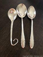 Three sterling silver spoons including a Gorham teaspoon, a Gorham sugar spoon, and a Denmark hammered sugar spoon shown on dark surface.