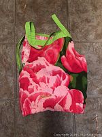 Full view of the folded apron showing vibrant pink flowers and green trim.