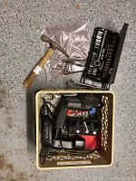 Photo of plastic basket holding two Black and Decker power tools with cords, claw hammer, and assorted drill bits.