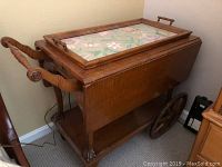 Photo of full drop leaf tea cart with removable floral tray on top and wheels visible