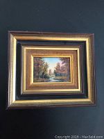 Framed porcelain landscape panel showing the full item with layered wooden and gold frame.