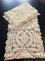 Photo of lace runner with folded placemats on top showing overall design and size context