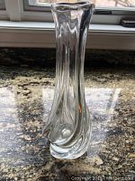Front view of the clear crystal bud vase on a granite surface showing the twisted swirl base and flared rim.