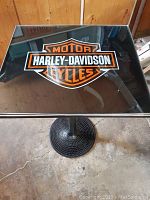 Black tempered glass square table top with large Harley-Davidson Motor Cycles logo in orange, white, and black colors.