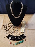 Wide arrangement showing chain necklace on bust, leather bead necklaces, rings on display, turquoise bracelet and earrings