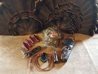 Full lot displayed with all items visible: 2 wild turkey feather plumes, 6 knives, compass, duck decoy, Thermacell mosquito repellent, youth Bass Pro Shop hat