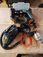 Overview of lot showing Scorpion car vacuum, Cobra radar detector, Black & Decker rotary tool and drill, switch and accessories on table surface
