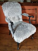 Front view of the antique chair with grey and black fun fur upholstery on seating and arms, showing wooden legs and armrest details.