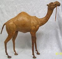 Side view of the leather dromedary camel figure showing its full length, including neck, hump, legs and tail.