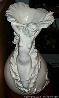 Frontal view showing mermaid figure supporting ruffled rim