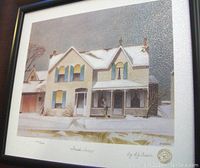 Front view of framed print showing the snow-covered house scene with signature and number visible at bottom.