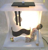 Front view of the frosted white Lucite lamp with black geometric details and ceramic lady figurine reclining inside the base.