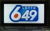 Front view of illuminated Lotto 649 sign with black frame and hanging chain visible, showcasing the bold blue, white and red logo design.