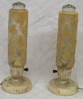 Front view of both lamps showing cylindrical frosted glass shades embossed with floral designs atop fluted round bases