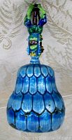 Front view of the bell showing turquoise blue cloisonne body in scale pattern and the detailed deity figurine handle in blue and green enamel.