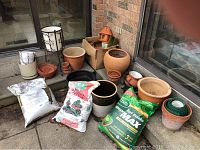 Full lot overview showing pots, bags of lawn food, top soil, metal plant stand, and green nursery tape.
