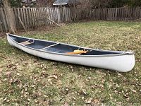 Full side profile of canoe on grass with paddles inside