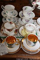 Overview of six Royal Albert teacups with matching floral saucers and three Czechoslovakia espresso cups with gold and green design.