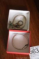 Overview of multiple pieces of sterling silver and turquoise jewelry including bracelets, rings, and an earring inside a white box and a red box.