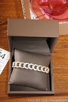 Sterling silver men's bracelet resting on cushion inside an open brown box.