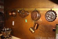 Copper measuring cups, embossed copper molds, and copper colander hanging on the wall.