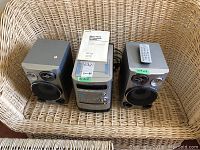 Full view of Sony micro hi-fi stereo system including central main unit, two speakers on each side, remote control placed on right speaker, and operating manual on top of main unit.