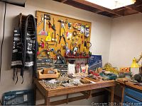 Workbench with assorted small hardware and tools displayed on pegboard and table.